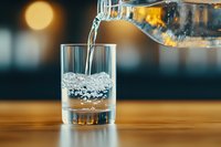 Pouring pure water from bottle into glass with bubbles and splashes on wooden table, bokeh background creates atmospheric mood. Fresh drink concept.