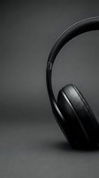Over-ear headphones with black leather ear cups and curved headband on neutral gray surface, suitable for audio equipment and music technology projects.