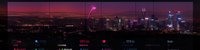 Neon-lit urban skyline at dusk with glowing pink and purple lights reflecting across modern city buildings and streets during twilight hours.