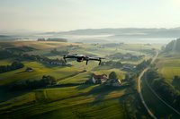 Drone flying over misty rural landscape with rolling hills, farmland, and winding road at sunrise. Aerial photography captures agricultural fields and scattered houses.