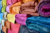 Colorful rolled fleece blankets stacked in rows showing vibrant rainbow colors and soft texture, creating cozy home decor display for retail or storage organization.