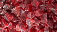 Red translucent crystal chunks with rough edges and facets create abstract geometric pattern with light reflections and shadows. Suitable for jewelry or mineral backgrounds.