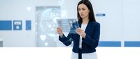 Professional businesswoman using transparent digital tablet with holographic interface in modern office environment for technology presentations.