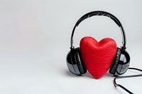 Red heart shape with black headphones on light background, music and love concept for valentines day cards, social media, and romantic playlists.