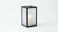 Modern black metal lantern with frosted glass panels and minimalist design, emitting soft ambient light for home decor and interior styling applications.