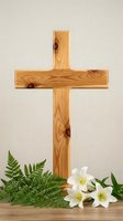 Wooden cross with white Easter lilies and green fern leaves on neutral background for religious holiday celebration and spiritual worship concepts.