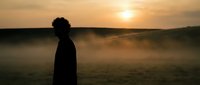 Young African American man silhouette standing in misty field during golden hour sunrise, contemplative mood for wellness and mindfulness content.
