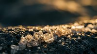 Golden chain jewelry lying on dark textured surface with warm bokeh lighting creating luxury accessories display for fashion and style concepts.