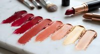 Professional makeup lipstick color palette swatches in warm tones from deep burgundy to nude beige with cosmetic brushes and tubes for beauty testing.