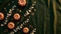 Autumn flat lay composition with orange pumpkins, eucalyptus branches and wooden buttons on dark green fabric background for seasonal design projects.