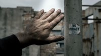 Male hand touching concrete barrier at abandoned industrial site, symbolizing loss, despair, and urban decay for editorial and conceptual projects.