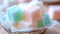 Colorful sugar-coated jelly candy cubes in pastel rainbow colors arranged in wire basket. Sweet confectionery treats for dessert and snack concepts.