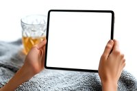 Young woman of African descent holding blank screen tablet while relaxing with beverage on cozy blanket. Mockup for digital lifestyle and technology design.