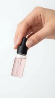 Hand holding pink nail polish bottle with black cap against white background for beauty and cosmetics applications.