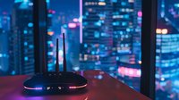 Modern wireless router with glowing LED lights against blurred urban nightscape background with bokeh city lights and skyscrapers through window.