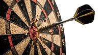 Dart hitting bullseye on dartboard showing precision, accuracy and target achievement for business success concepts and competitive sports games.