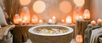 Spa wellness bowl with floating flowers and candles creating peaceful ambiance for relaxation and self-care rituals in serene candlelit atmosphere.