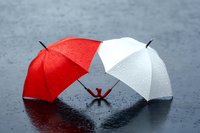 Two colorful umbrellas red and white lying on wet asphalt surface with water droplets creating reflections during rainy weather protection concept.