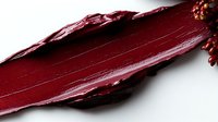 Deep burgundy lipstick smear showing rich, creamy texture against white background, demonstrating luxurious cosmetic product color and consistency for beauty marketing.