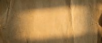 Aged paper texture with warm golden tones and creased surface, suitable for vintage backgrounds, scrapbooking, and retro design projects.