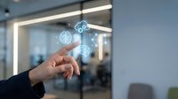 Hand touching glowing digital brain and AI icons on glass surface in modern office environment for technology and innovation concepts.