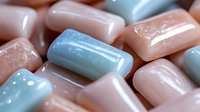 Macro shot of pink and blue pharmaceutical capsules or pills in soft pastel colors showing medical texture pattern and healthcare concept.