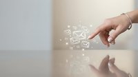 Young woman's hand touching digital envelope icons floating above a reflective surface, representing email communication, messaging, and digital contact solutions.