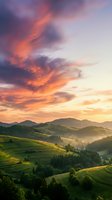 Dramatic sunset sky with vibrant orange and purple clouds over rolling green hills, forested mountains, and misty valleys. Ideal for travel, nature, and landscape projects.