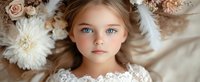 Young girl with bright blue eyes surrounded by soft pink roses and white chrysanthemums, wearing delicate lace dress, ethereal portrait with dreamy floral composition.