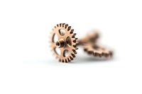 Copper mechanical gears on white background with selective focus and shallow depth of field, industrial machinery parts and components.