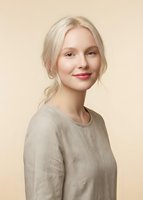 Young blonde Caucasian woman in beige linen shirt smiling confidently at camera against neutral background for business and lifestyle concepts.