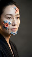 Young Asian woman with kintsugi-inspired floral face art, gold cracks and ceramic flowers on skin, dark background, beauty concept.