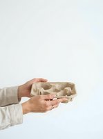 Person with medium skin tone holding empty cardboard egg carton against white background, suitable for sustainability, recycling, waste reduction, and eco-friendly packaging concepts.