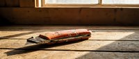 Old leather-bound book resting on rustic wooden floor in warm sunlight streaming through window. Vintage literature concept for education and reading.