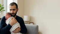 Young father with dark hair and beard, Middle Eastern ethnicity, holding newborn baby wrapped in white blanket indoors. Parenting, family bonding, new parenthood concept for healthcare and lifestyle use.