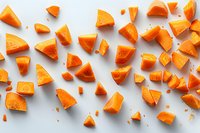 Fresh cut butternut squash pieces scattered on white background, overhead view. Perfect for cooking, recipe, and food blog designs, showing raw vegetable preparation.