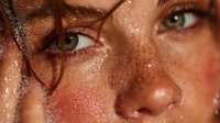 Close-up portrait of young woman with freckles and wet skin covered in water droplets, natural beauty skincare concept for cosmetics advertising.