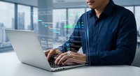 Professional businessman analyzing financial data and stock market charts on laptop computer in modern office environment for investment decisions.