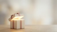 Striped gift box with open lid revealing glowing light inside, isolated on wooden surface with soft blurred background for holiday and celebration designs.