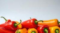 Fresh colorful bell peppers in red, orange and yellow varieties arranged on white background for healthy cooking and nutrition concepts.