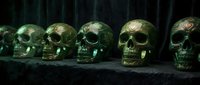 Golden skull sculptures arranged in a row on dark surface with moody lighting, suitable for gothic, Halloween, horror, and dark fantasy design projects.