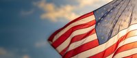 American flag waving against dramatic sky with wooden pole, patriotic symbol for Independence Day, Memorial Day, Veterans Day celebrations and national pride.