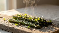Grilled asparagus spears with herbs and seasoning steaming on rustic wooden cutting board in warm kitchen setting for healthy cooking recipes.