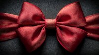Elegant red silk bow tie on dark leather background for formal events, weddings, and special occasions. Classic menswear accessory for sophisticated style.