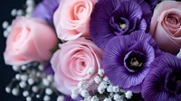 Romantic floral arrangement featuring soft pink roses and vibrant purple lisianthus blooms with delicate white baby's breath against dark background.