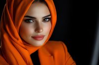 Young Middle Eastern woman wearing bright orange hijab and matching outfit against dark background, dramatic lighting highlights facial features and fabric texture.