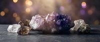 Collection of healing crystals and gemstones including amethyst, quartz and pyrite arranged on dark surface with warm bokeh lighting for wellness.