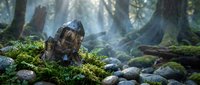 Ancient stone sculpture head covered in moss nestled among rocks in mystical forest with sunbeams filtering through trees creating ethereal atmosphere.