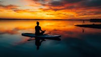 Silhouette of person meditating on paddleboard at sunset with dramatic orange sky reflecting on calm water creating peaceful mindfulness scene.