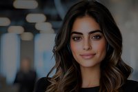 Young woman with long wavy brown hair and olive complexion, wearing black top, posed against blurred urban background with bokeh lighting for portrait and professional use.